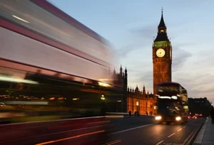 Big Ben and driving fast red double-decker buses in London, UK